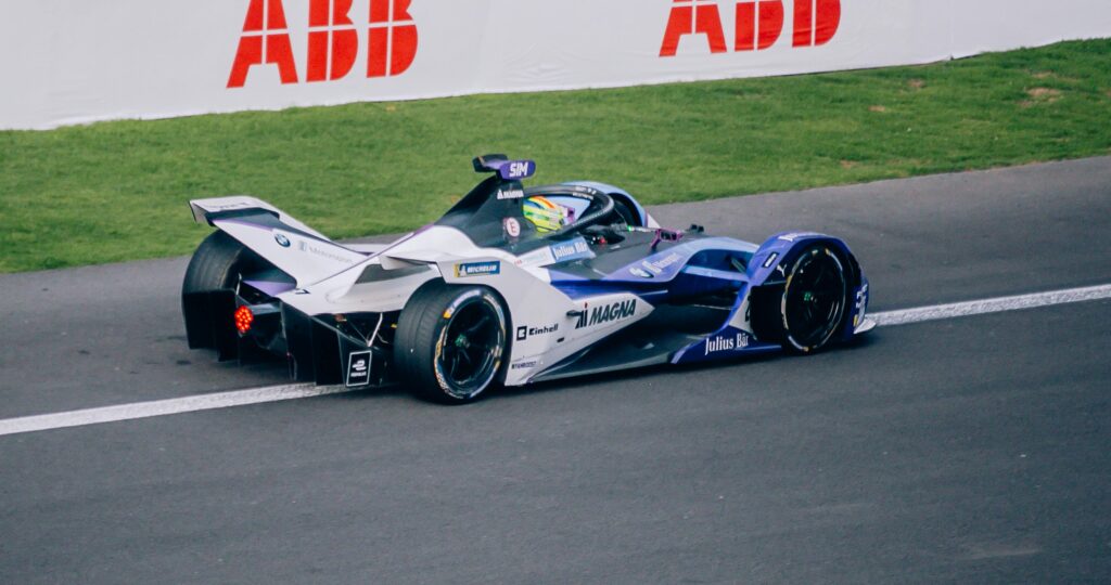 A Formula E race car speeds on track at a racing event in Mexico City, showcasing high-tech engineering.
