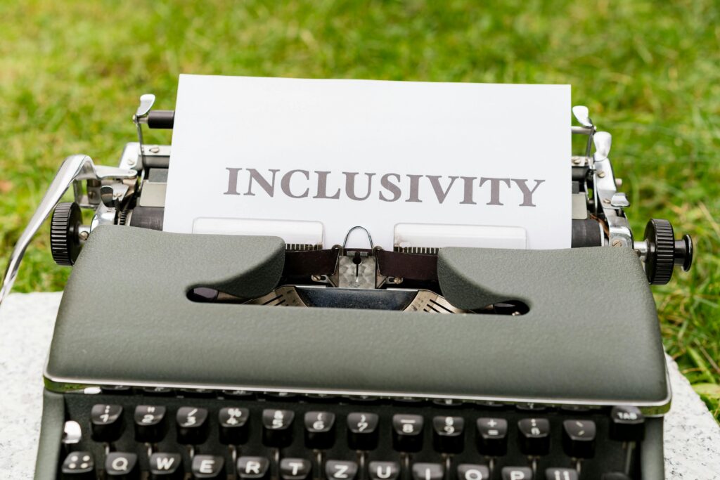A vintage typewriter with a sheet displaying 'Inclusivity' on a lush green background.