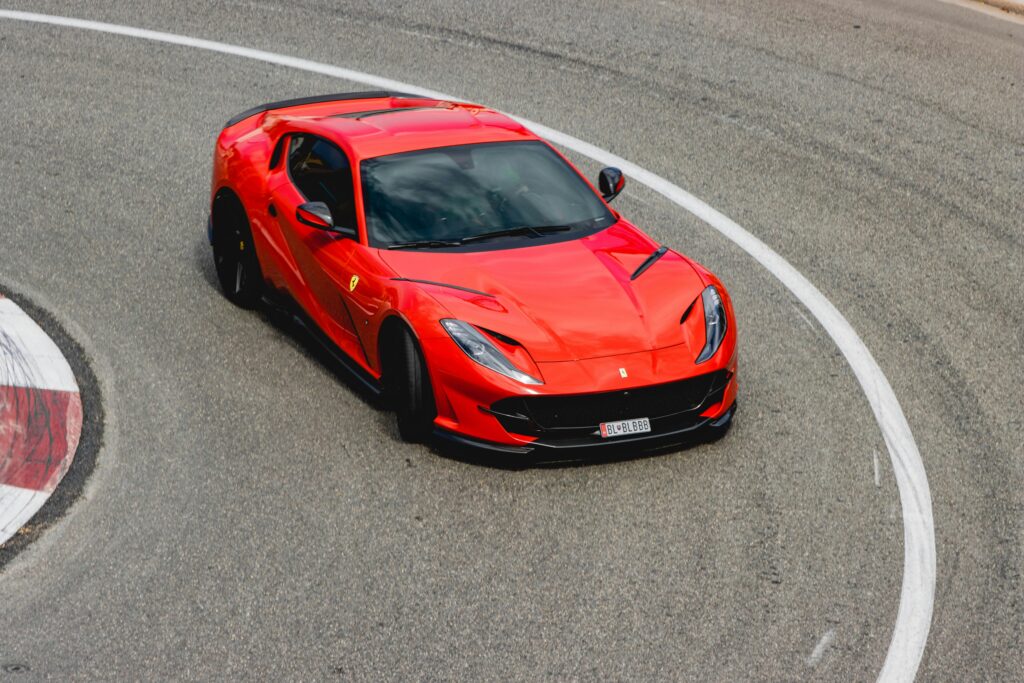 Dynamic image of a red sports car maneuvering a sharp curve on a Monaco racetrack.